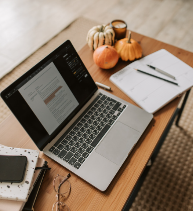 Photo of a laptop, notebook, and pen on a desk